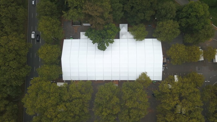 Luftaufnahme eines Messezelts zwischen Bäumen