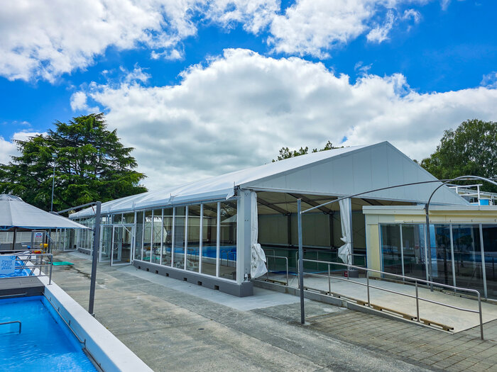 Pool enclosure for swimming pool complex under partly cloudy skies