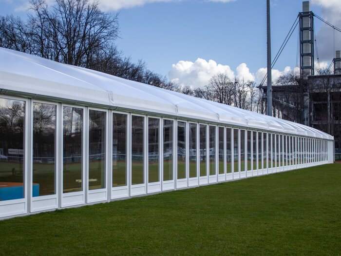 Leichtbauhalle mit durchgehender Fensterfront auf einer grünen Wiese in Köln