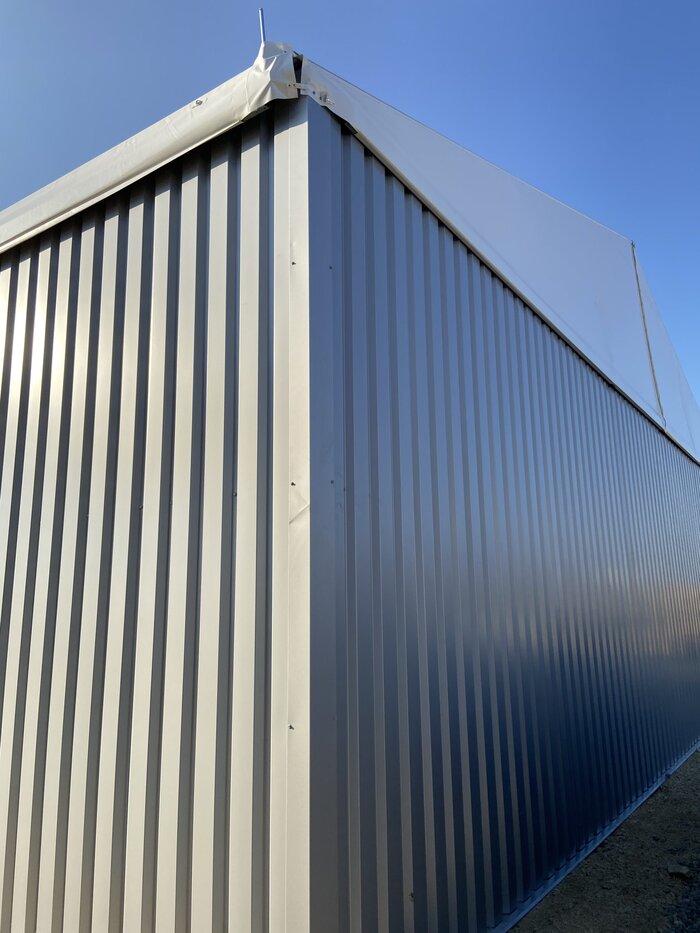 Corner of a mobile warehouse with trapezoidal sheet metal wall and PVC roof
