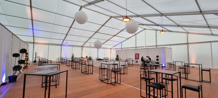Innenansicht eines weißen Eventzeltes mit moderner Stehtischbestuhlung