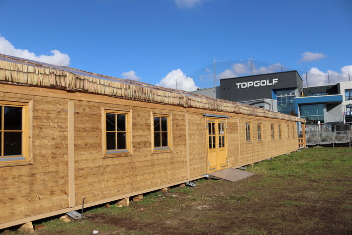 Seitansicht eines Festzelts im Holz-Design auf Wiese