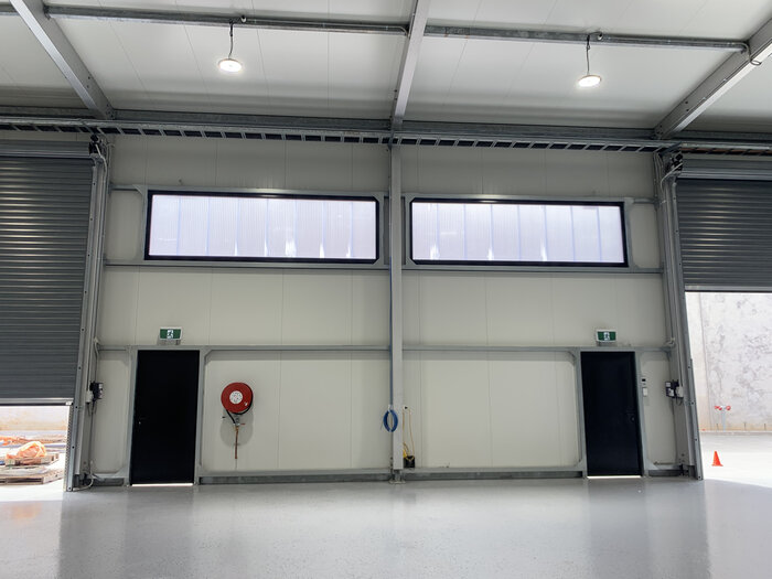 Interior wall of a warehouse with roller shutters and emergency exits