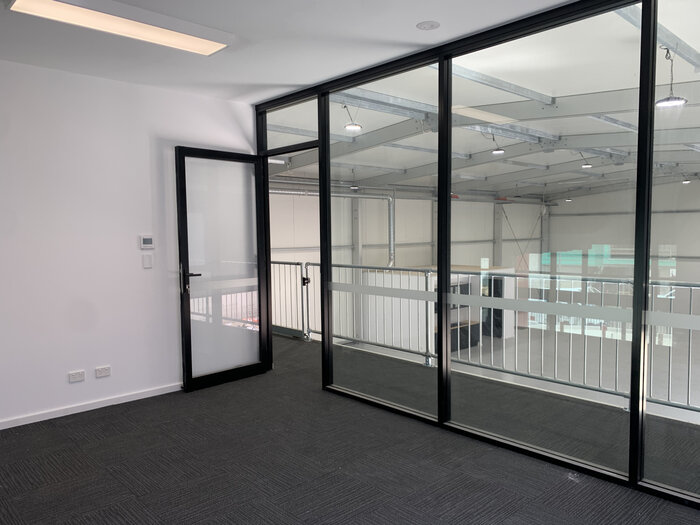 Interior view of an office with glass wall on the upper floor of a warehouse