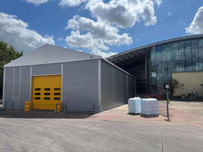 Isolierte Lagerhalle mit gelbem Rolltor neben Industriegebäude