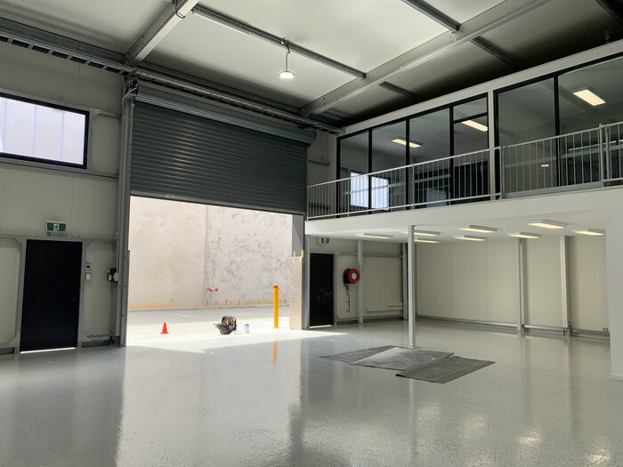 Modern warehouse with roller shutter door and office unit on the upper floor