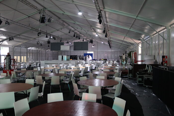 Innenansicht eines großen Messezelts mit runden Tischen