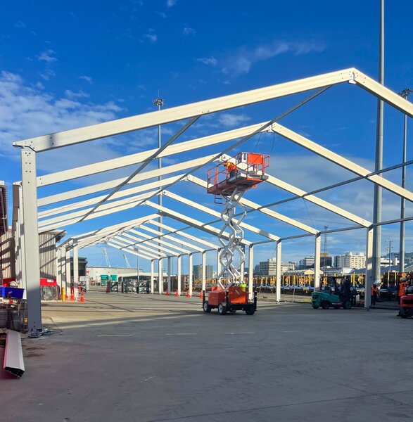 Construction of an aluminium-framed industrial building with lifting platform and pre-assembled frame sections on an industrial site