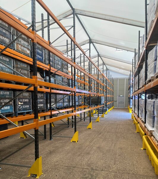 Interior view of an aluminium-framed warehouse building with shelving systems and translucent roof