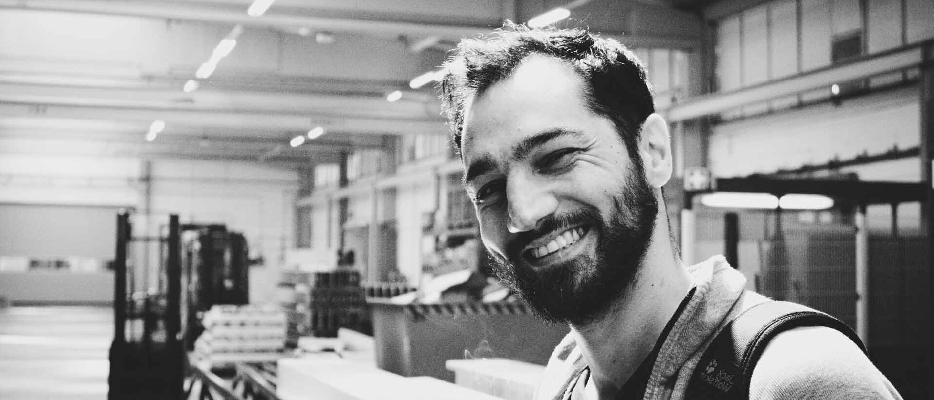 Lächelnder Mitarbeiter in Produktionshalle von HR-Structures