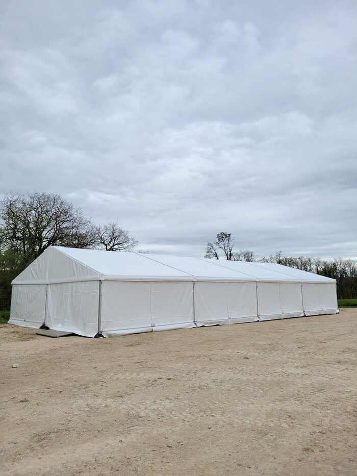 Seitenansicht eines weißen Veranstaltungszelts auf freiem Gelände