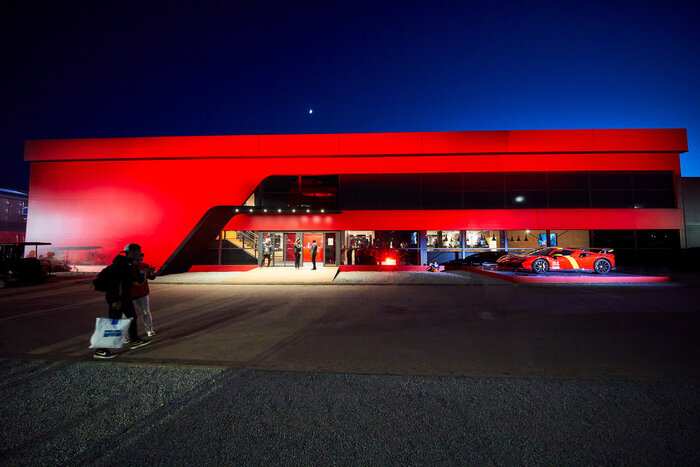 Frontansicht eines Skyline-Eventzelts mit roter Fassade und Sportwagen bei Nacht