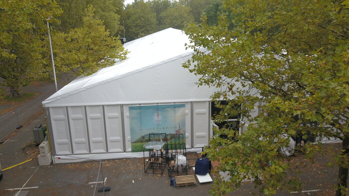 Weißes Messezelt im Freien unter Bäumen