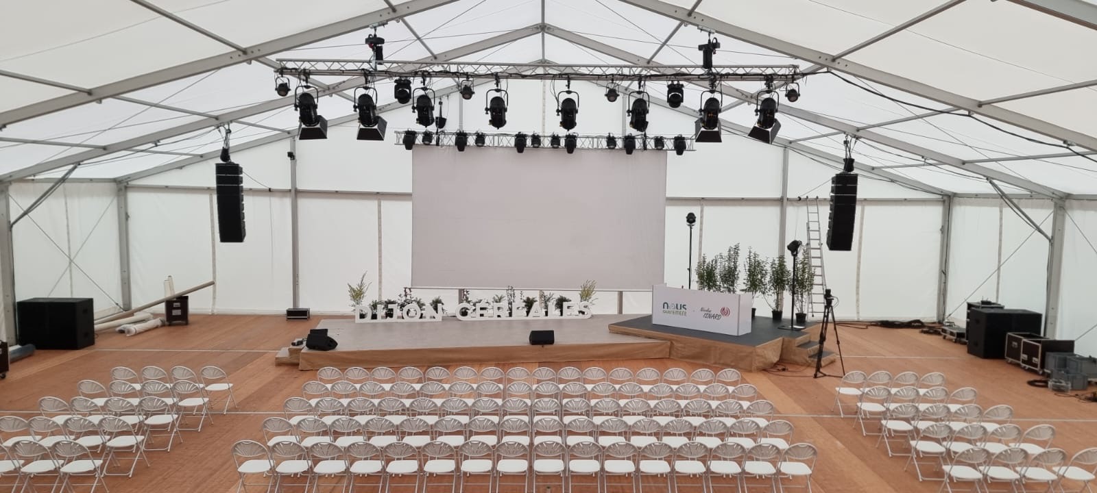 Innenansicht eines weißen Eventzeltes mit Bühne und Bestuhlung